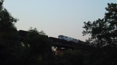 AmTrak Train coming over the Trestle in Austin, Texas. The veiw is in silhouette from below and the train's headlight is clearly visible.