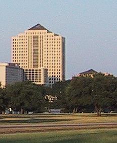 Same as the previous picture, but with sharper detail... The San Jacinto Building - Appears as a Bleak Yellow Multi-story Building with Distinctive Black Windows and a Gable Atrium at the Top of the Building.