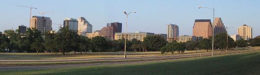 A View of the Austin Downtown Skyline looking from the South, a grassy park is in the foreground.