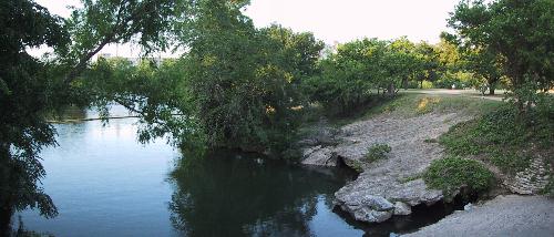 A Rocky Outcroping on the right leeds to Still Water which is Surrounded by Trees.