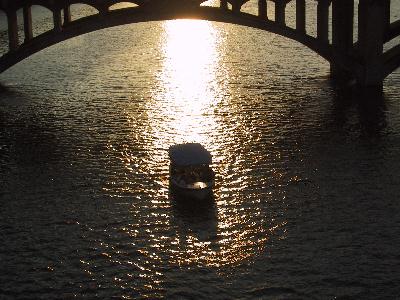 A Tighter Shot of another Boat in the Reflective Sunset on the Colorado Rover under the Lamar Street Bridge.  ''Austin Cruises''