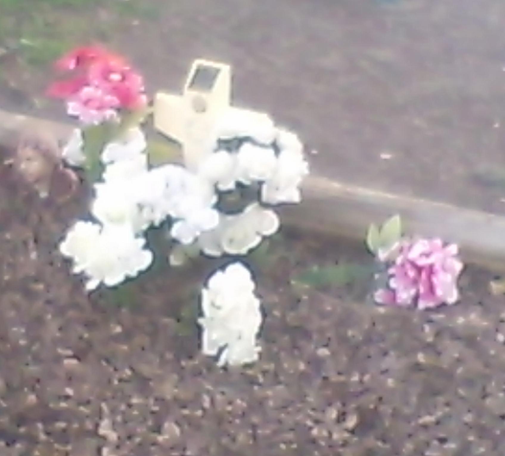 A White Cross and Plastic Flowers left by someone on the property.